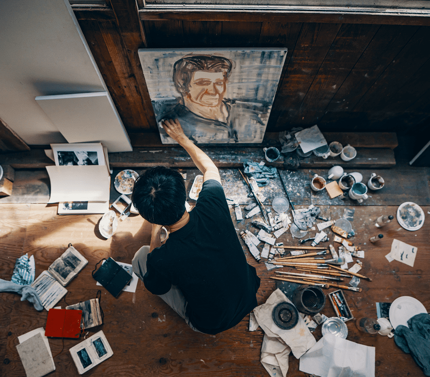 Painter working on canvas, surrounded by tools